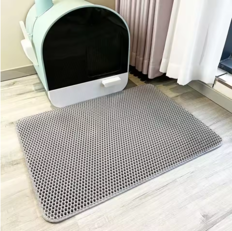 Tapis de litière pour chat double couche gris devant un bac à litière.